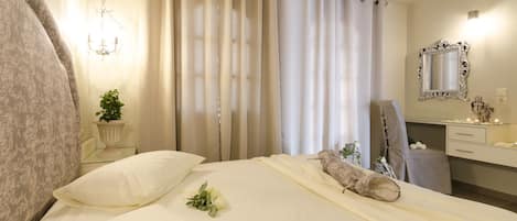 Habitación de hotel con una cama, un tocador con espejo, una planta y un candelabro.