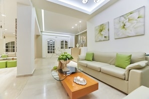 A modern living room with a sofa, a glass coffee table, and artwork on the wall.