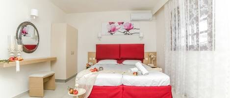 A modern bedroom with a large bed, a bedside table, a mirror, and a wall-mounted air conditioner.