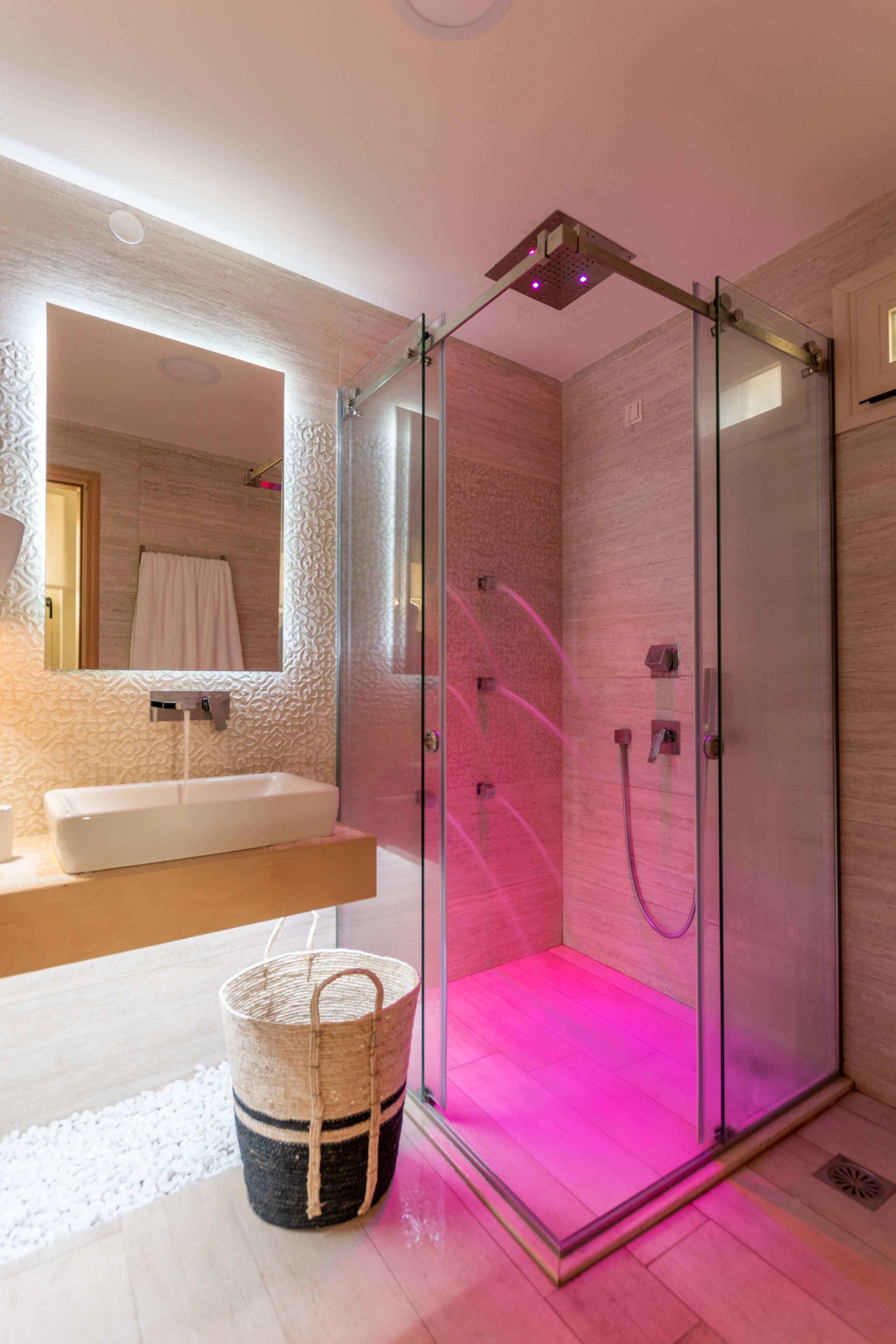 A modern bathroom with a glass-enclosed shower, a sink, and a mirror.
