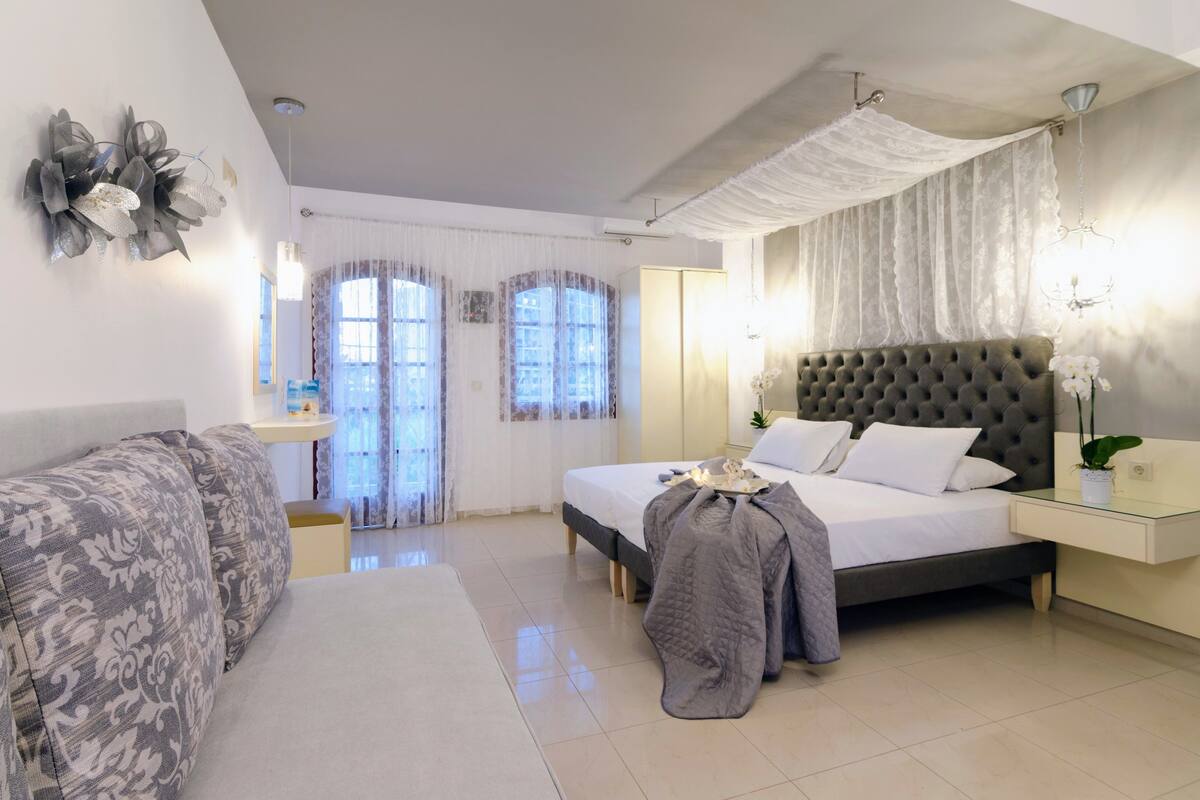 A bedroom with a bed, bedside table, and a sofa.