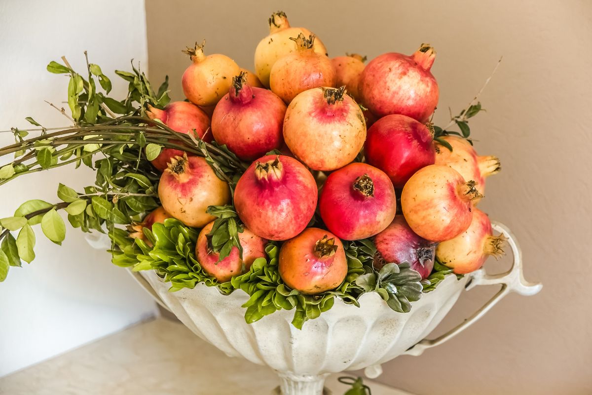 A pomegranate bouquet in a white ceramic vase.