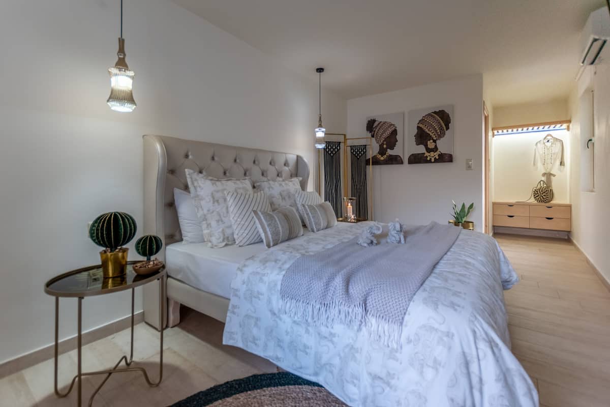 A bedroom with a large bed, bedside tables, a nightstand, and a dresser.