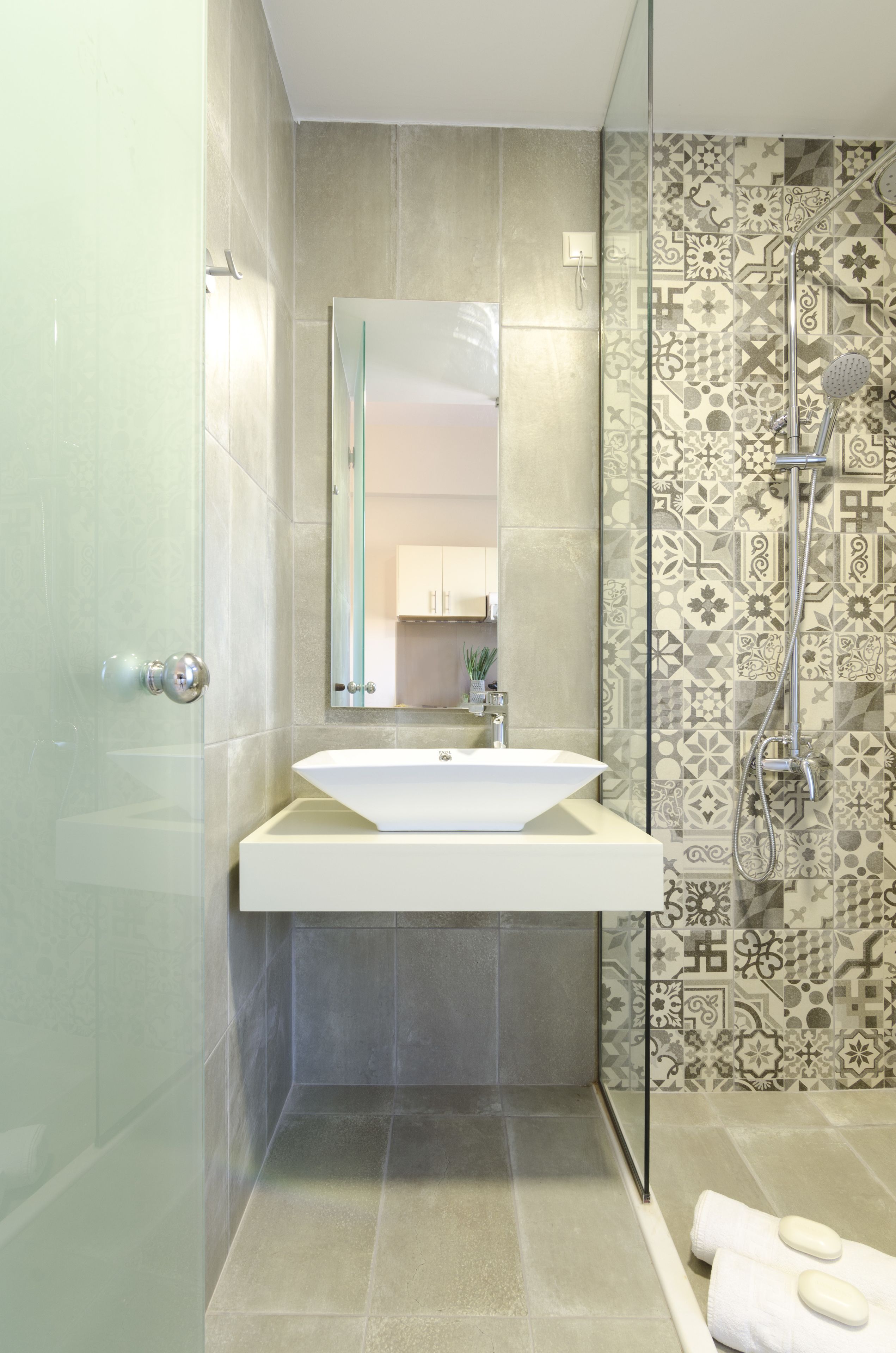 A modern bathroom with a large mirror, a white sink, and a shower area.