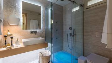 Un baño moderno con ducha envuelta en vidrio, un espejo grande y un lavamanos blanco.