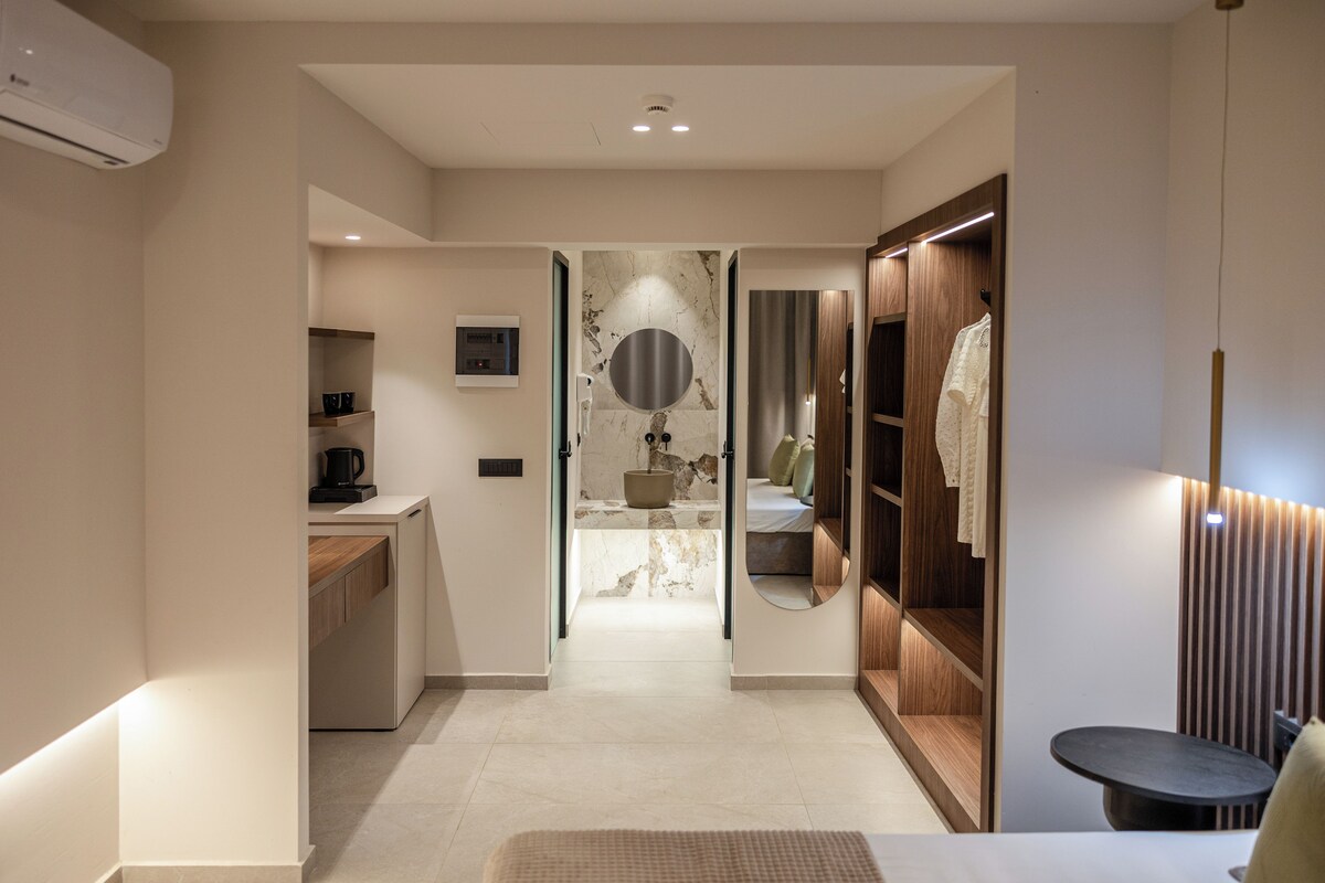 Un baño moderno con lavamanos de mármol, un espejo grande y un mueble de tocador de madera.