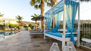 Zona de piscina con sillones de descanso, una sombrilla y vistas a la piscina y al paisaje circundante.