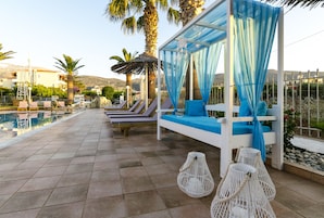 Zona de piscina con sillones de descanso, una sombrilla y vistas a la piscina y al paisaje circundante.