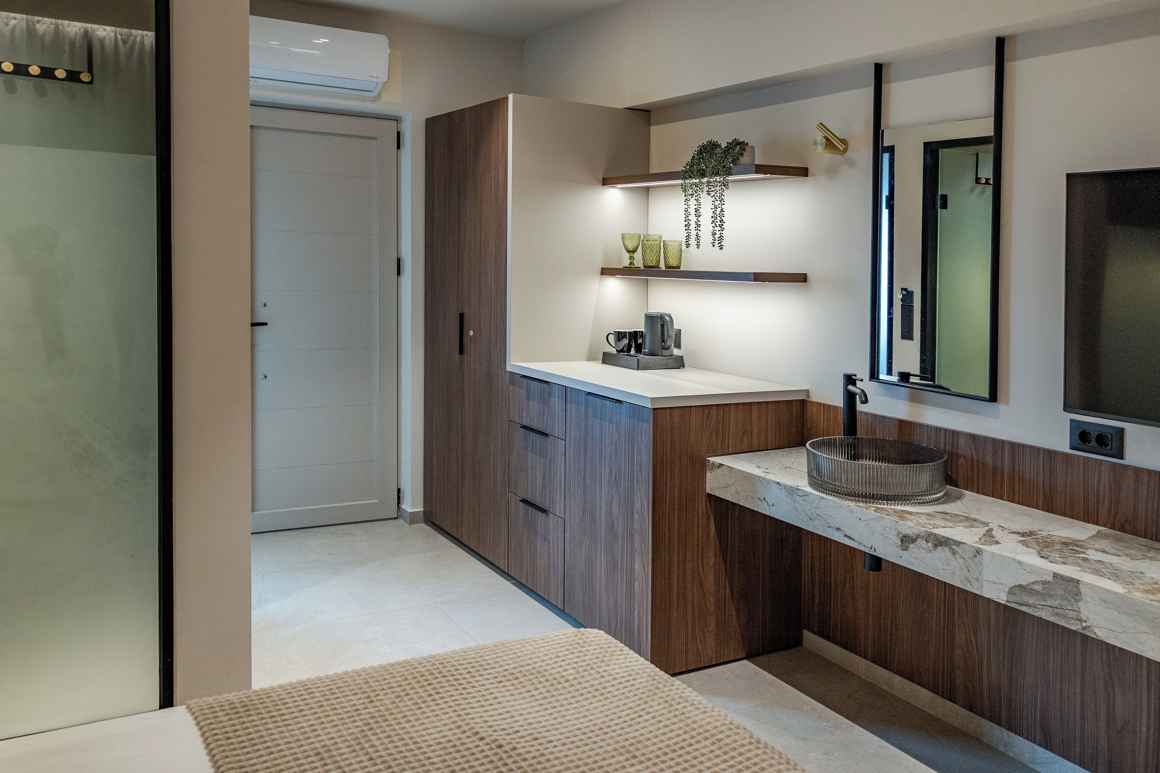 A modern bathroom with a wooden vanity, a mirror, and a built-in shelf with decorative items.