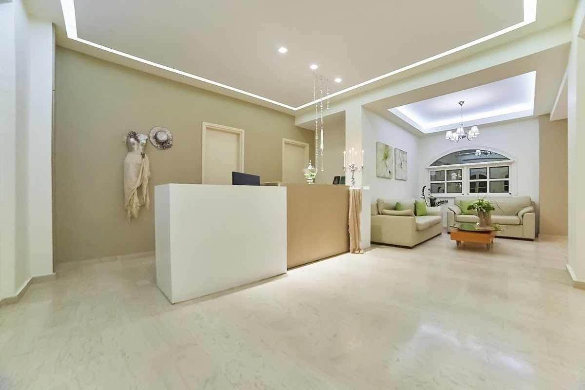 A modern reception area with a white reception desk, a sofa, and a chandelier.