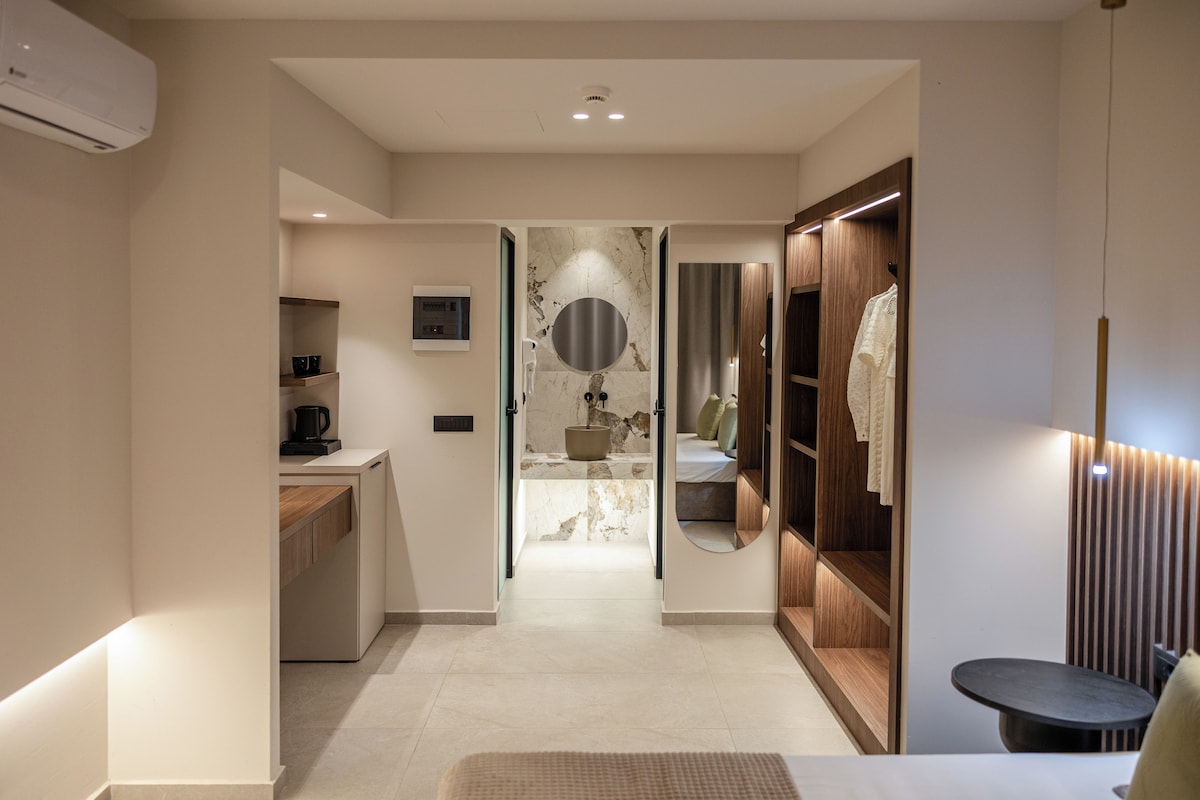 Un baño moderno con lavamanos de mármol, un espejo grande y un mueble de tocador de madera.