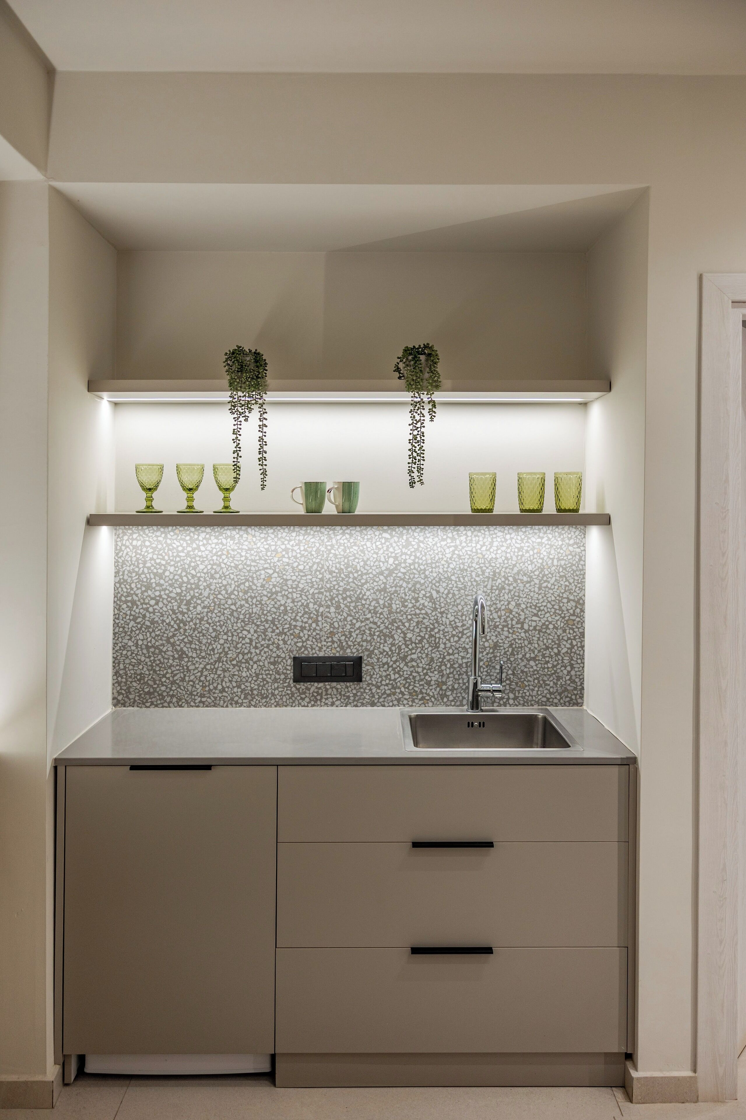 A compact kitchen with a tiled backsplash, a stainless steel sink, and a countertop.