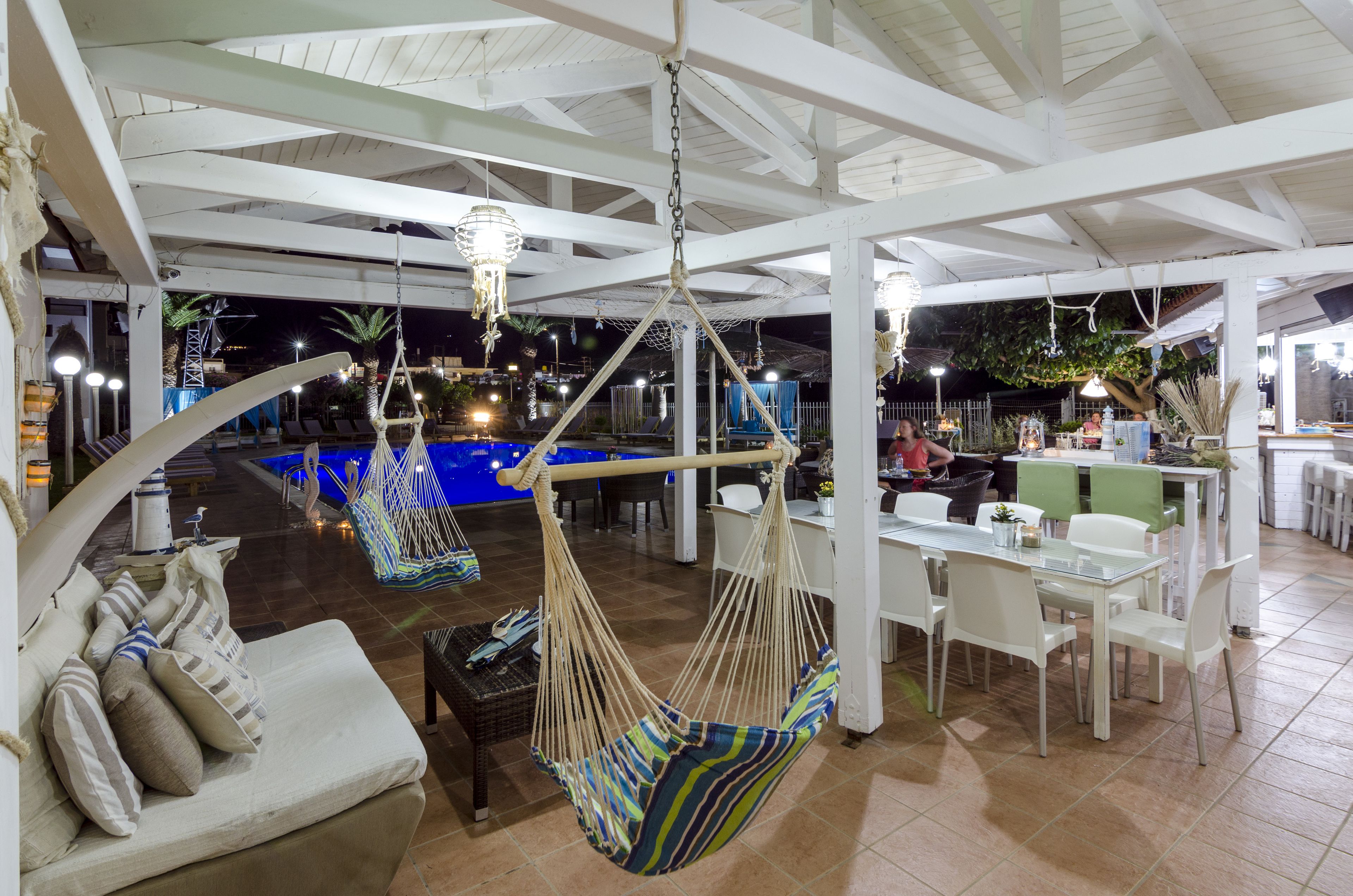A covered outdoor area with a pool, seating, and hanging hammocks.