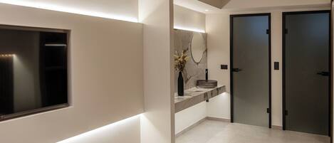 Un baño moderno con un espejo grande, un lavamanos integrado y un inodoro.