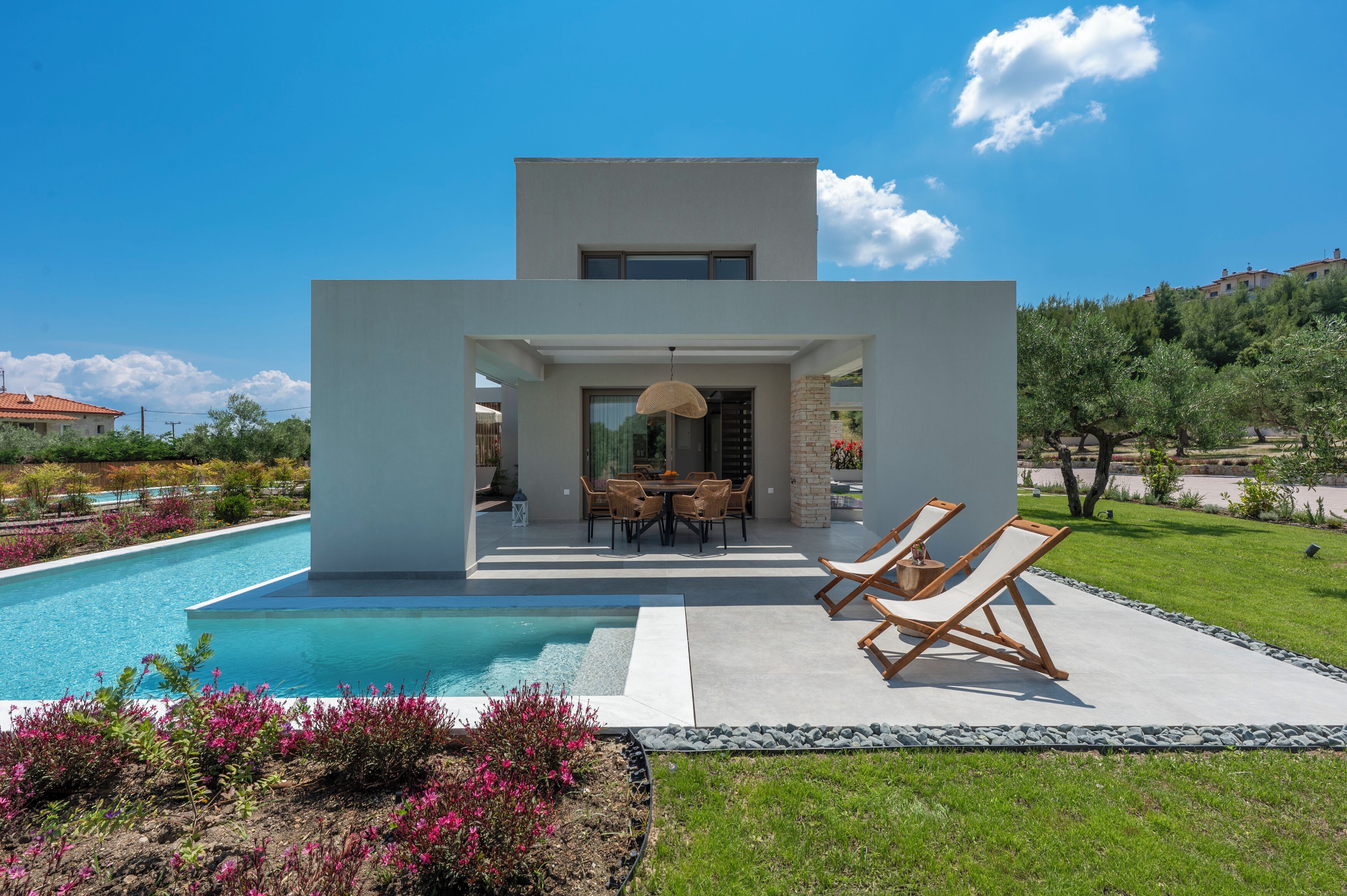 Una casa moderna con piscina, mobiliario de exterior y zona de comedor.