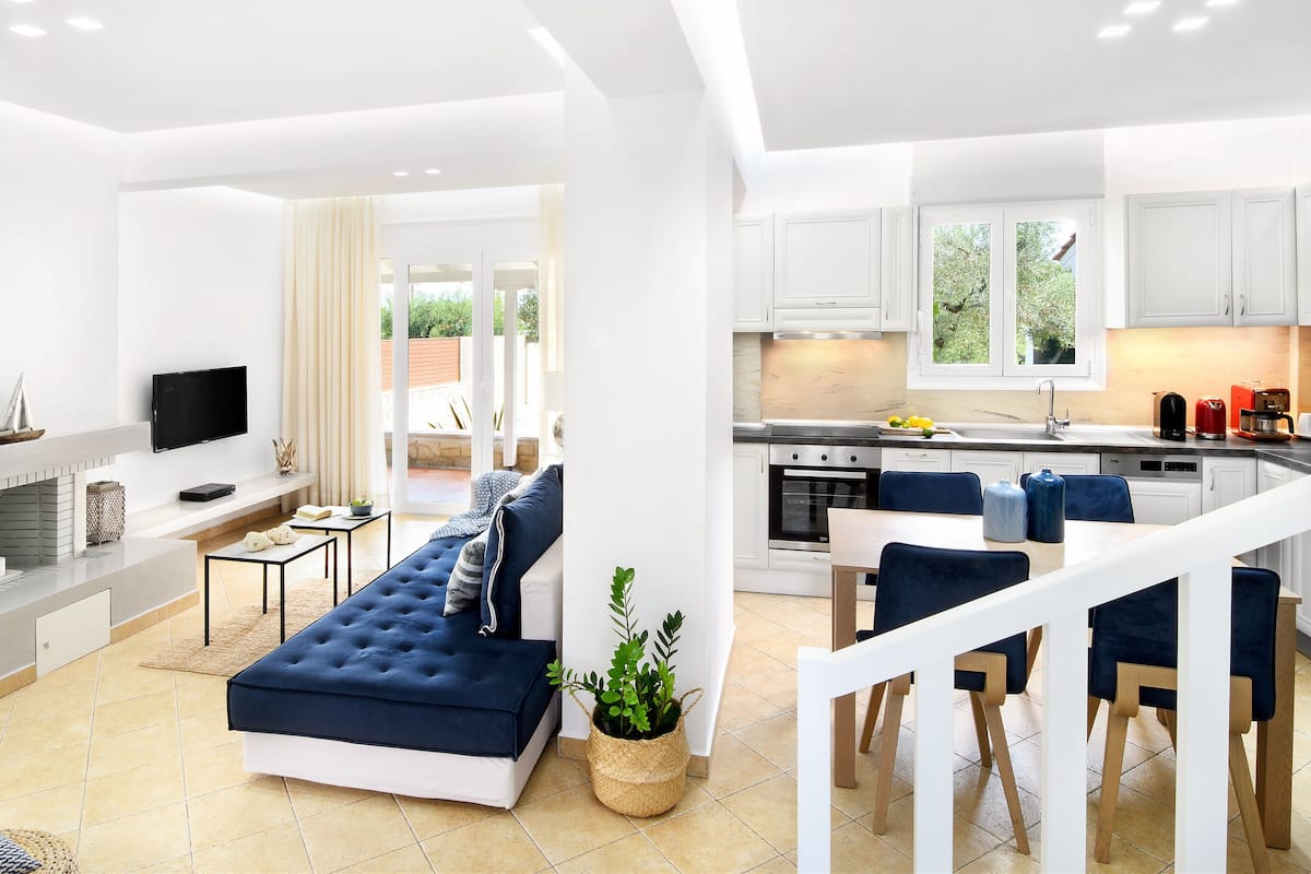 A modern living room with a sofa, TV, fireplace, and a view to the outside.