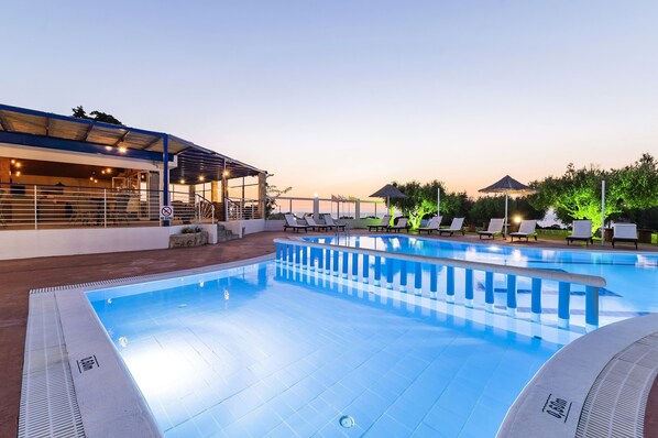 Una piscina al aire libre de temporada, sombrillas