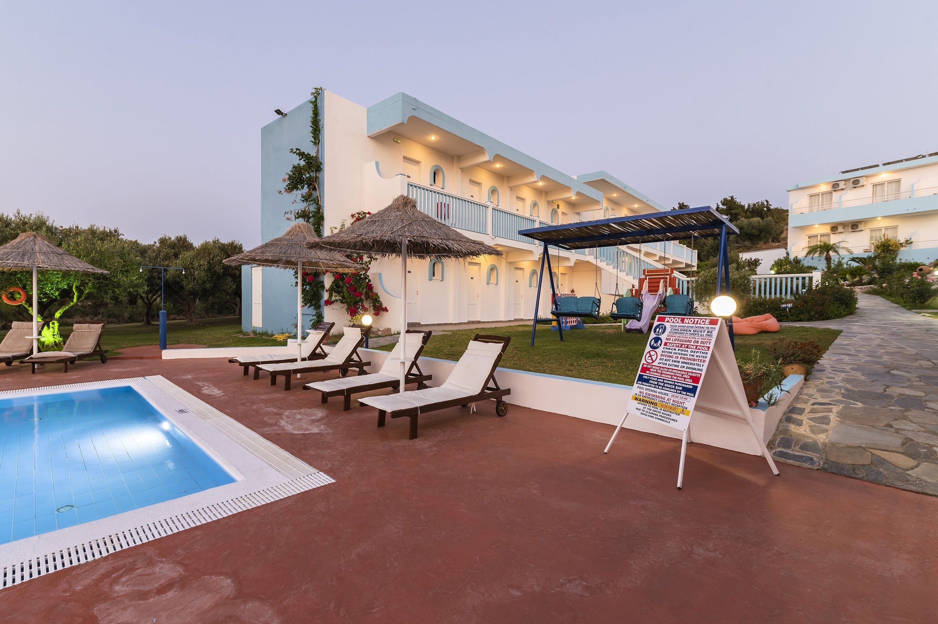 A pool area with lounge chairs and a signboard.