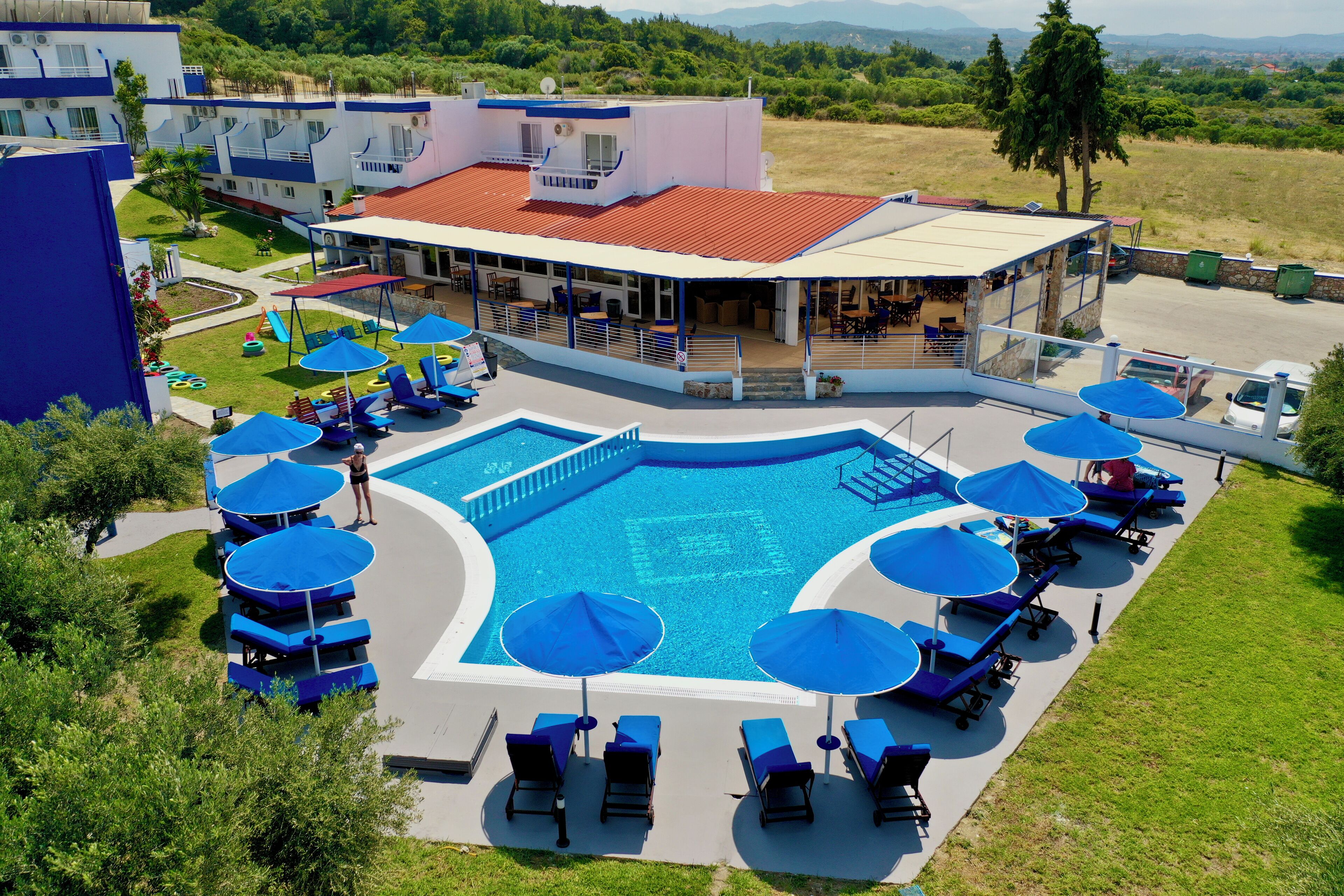 Um hotel com piscina, espreguiçadeiras e guarda-sóis.