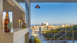 Un balcon avec vue sur la ville, une bouteille, des verres et des coussins décoratifs.