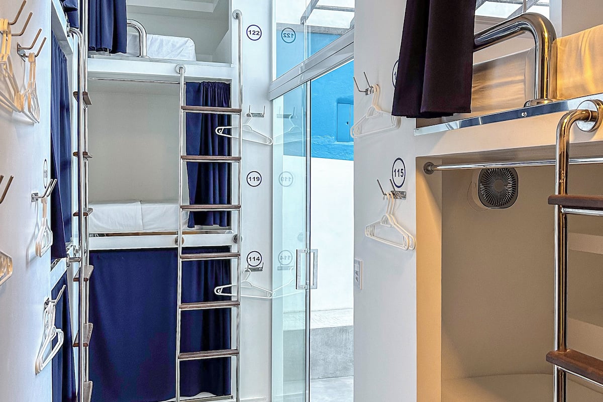 Een compacte, moderne kamer met stapelbedden, een glazen deur naar buiten en een airconditioning.
