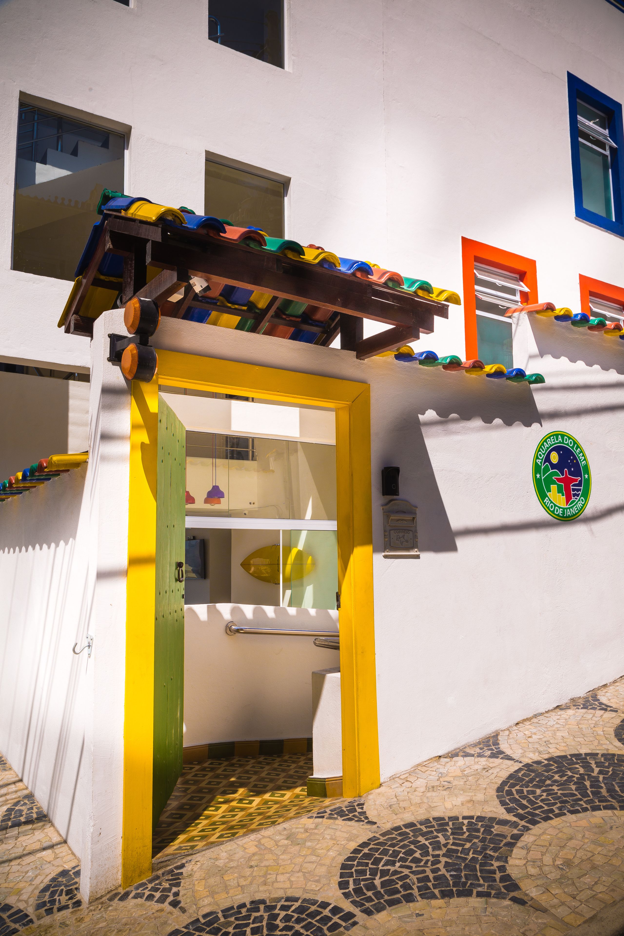 Entrada de un edificio con una estructura de juego colorida, piso de baldosas y un emblema en la pared.