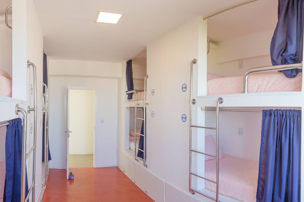 Een studentenkamer met stapelbedden, een deur en een raam.