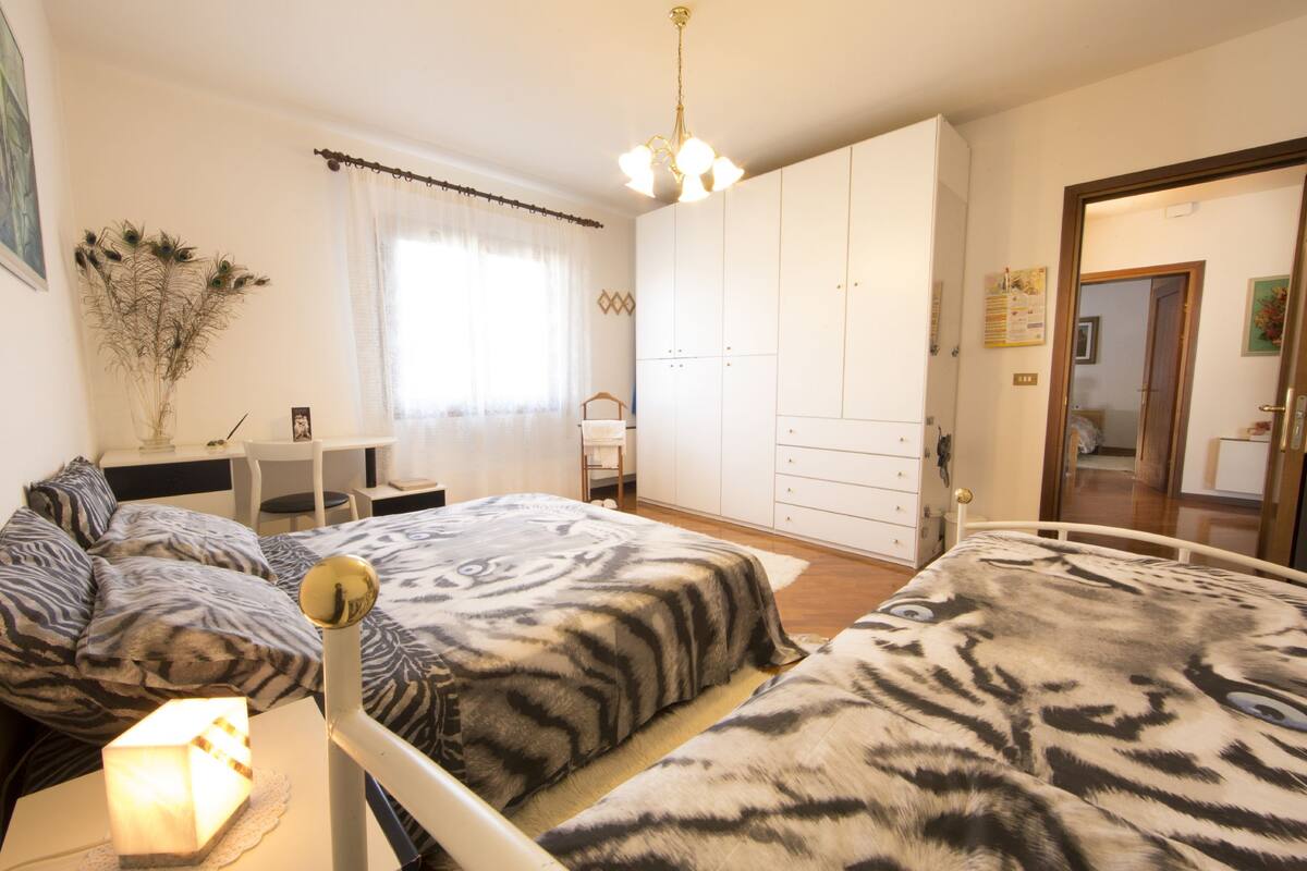 A bedroom with two beds, a desk, and a wardrobe.
