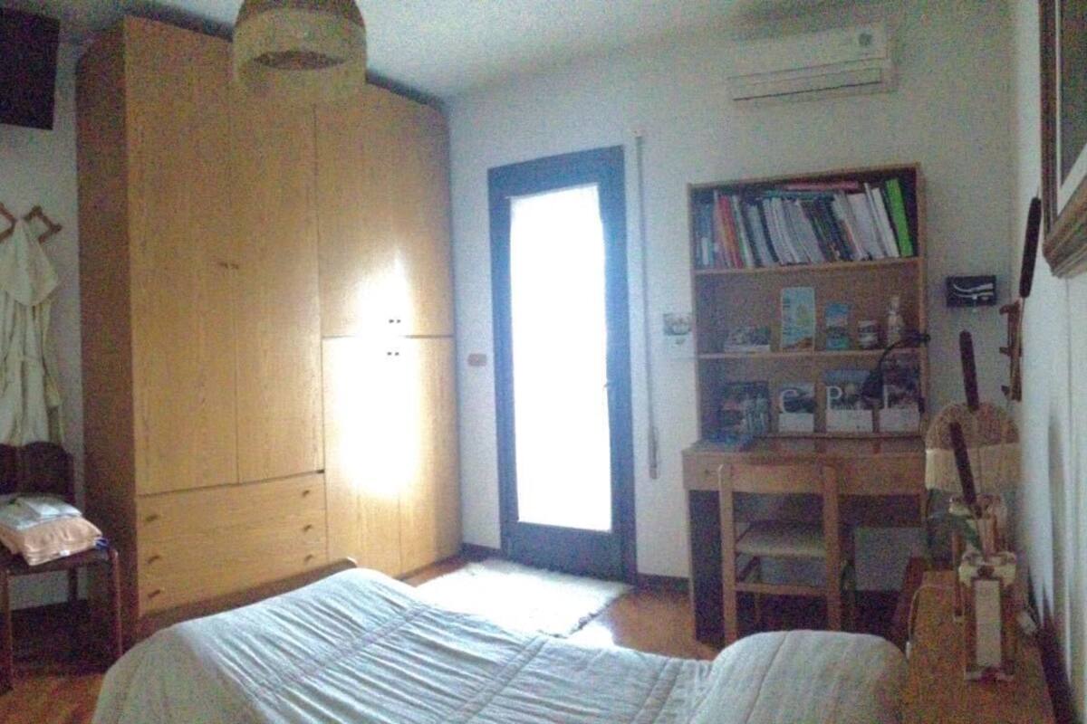 A bedroom with a bed, a wardrobe, a desk with a chair, and a bookshelf.