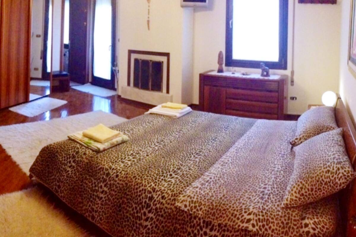 A bedroom with a large bed, a dresser, a mirror, and a television.