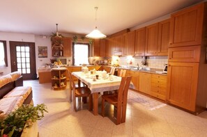 Una cocina luminosa con armarios de madera, una mesa de comedor preparada para cuatro personas y una zona de estar acogedora con un sofá.