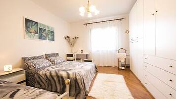 A bedroom with a bed, bedside tables, a dresser, and a window with curtains.
