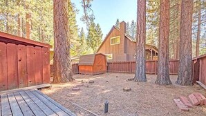 A wooden cabin with a deck, surrounded by tall trees. - 1198 Carson Avenue 1 Bedroom Cabin by RedAwning (South Lake Tahoe)