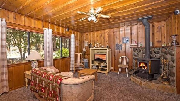 A cozy cabin interior with a fireplace, wooden walls, a sofa, and a television. - 1198 Carson Avenue 1 Bedroom Cabin by RedAwning (South Lake Tahoe)