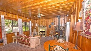 A cozy cabin interior with wooden walls, a fireplace, a dining table, and a sofa. - 1198 Carson Avenue 1 Bedroom Cabin by RedAwning (South Lake Tahoe)