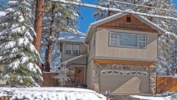 A two-story house with a garage, surrounded by snow-covered trees. - 1209 Golden Bear 3 Bedroom Home by RedAwning (South Lake Tahoe)
