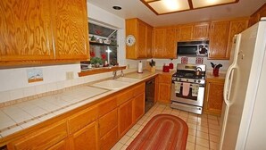 A kitchen with wooden cabinets, a stove, a sink, and a refrigerator. - 1209 Golden Bear 3 Bedroom Home by RedAwning (South Lake Tahoe)