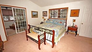 A bedroom with a bed, a nightstand, a chair, a window, and a door. - 1209 Golden Bear 3 Bedroom Home by RedAwning (South Lake Tahoe)