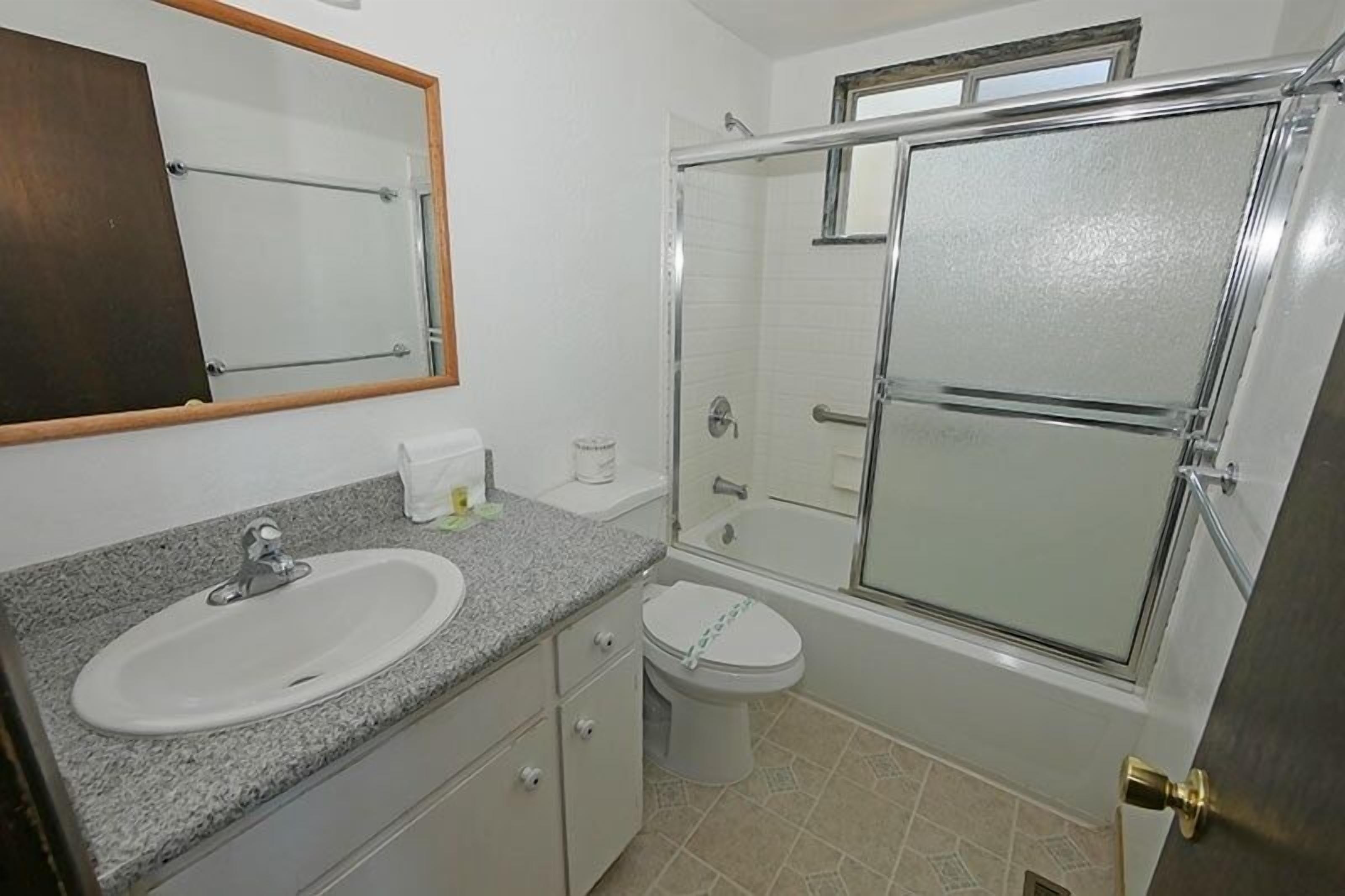 A bathroom with a sink, toilet, and glass-enclosed shower.