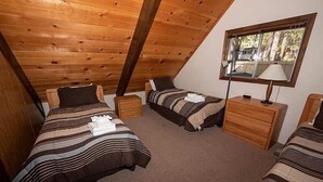 A cozy attic bedroom with two beds, wooden headboards, a window with a view, and a bedside lamp. - 1360 Knoll Lane 3 Bedroom Home by RedAwning (South Lake Tahoe)