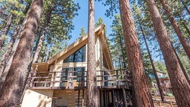 A cabin with a balcony, surrounded by tall pine trees. - 1360 Knoll Lane 3 Bedroom Home by RedAwning (South Lake Tahoe)