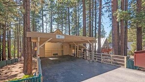 A covered outdoor area with a wooden structure, possibly a shelter or a small building, surrounded by tall pine trees. - 1360 Knoll Lane 3 Bedroom Home by RedAwning (South Lake Tahoe)
