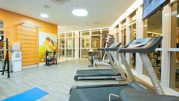 Ein Fitnessstudio mit Laufbändern, Gewichten und einer blauen Trainingsmatte.