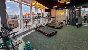 Un gimnasio con cintas de correr, máquinas de pesas y un espejo grande.