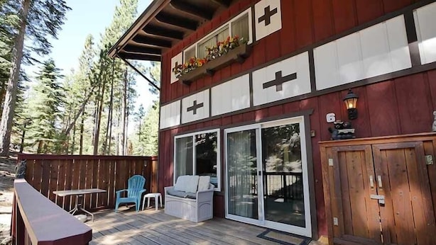 A wooden deck with a covered seating area, a sliding glass door, and a wooden gate. - 1510 Wildwood, 6 2 Bedroom Condo by RedAwning (South Lake Tahoe)