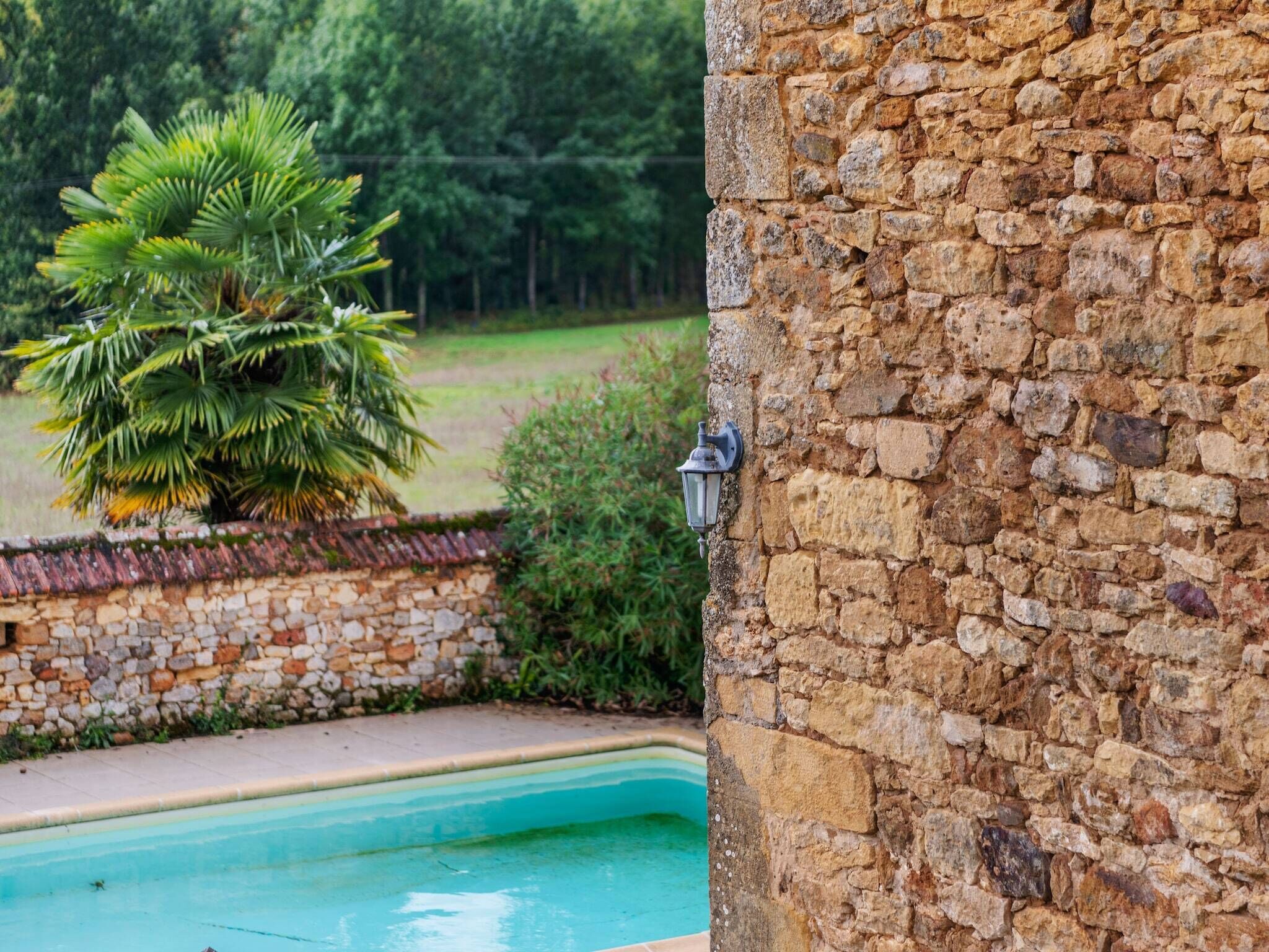 A stone wall with a pool and a lamp.