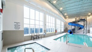 An indoor swimming pool with a hot tub, a blue water slide, and a lifeguard warning sign. - Holiday Inn Express Red Deer North by IHG (Red Deer)