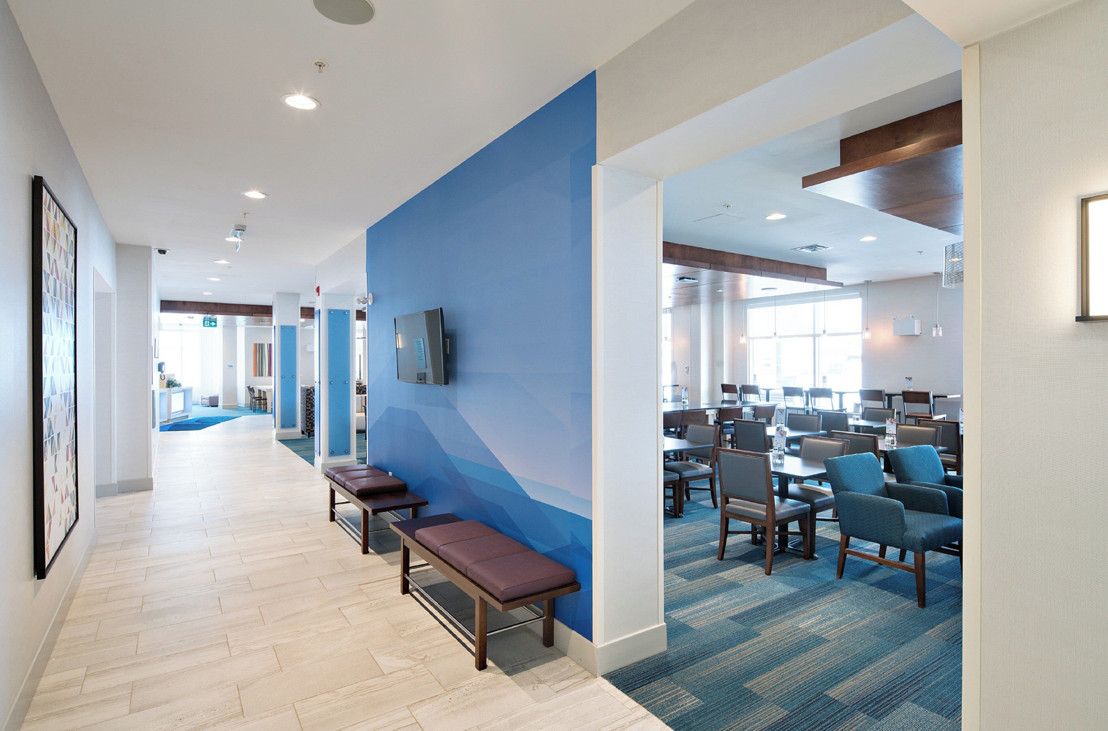 A hotel lobby with a long corridor, seating area, and a dining section.