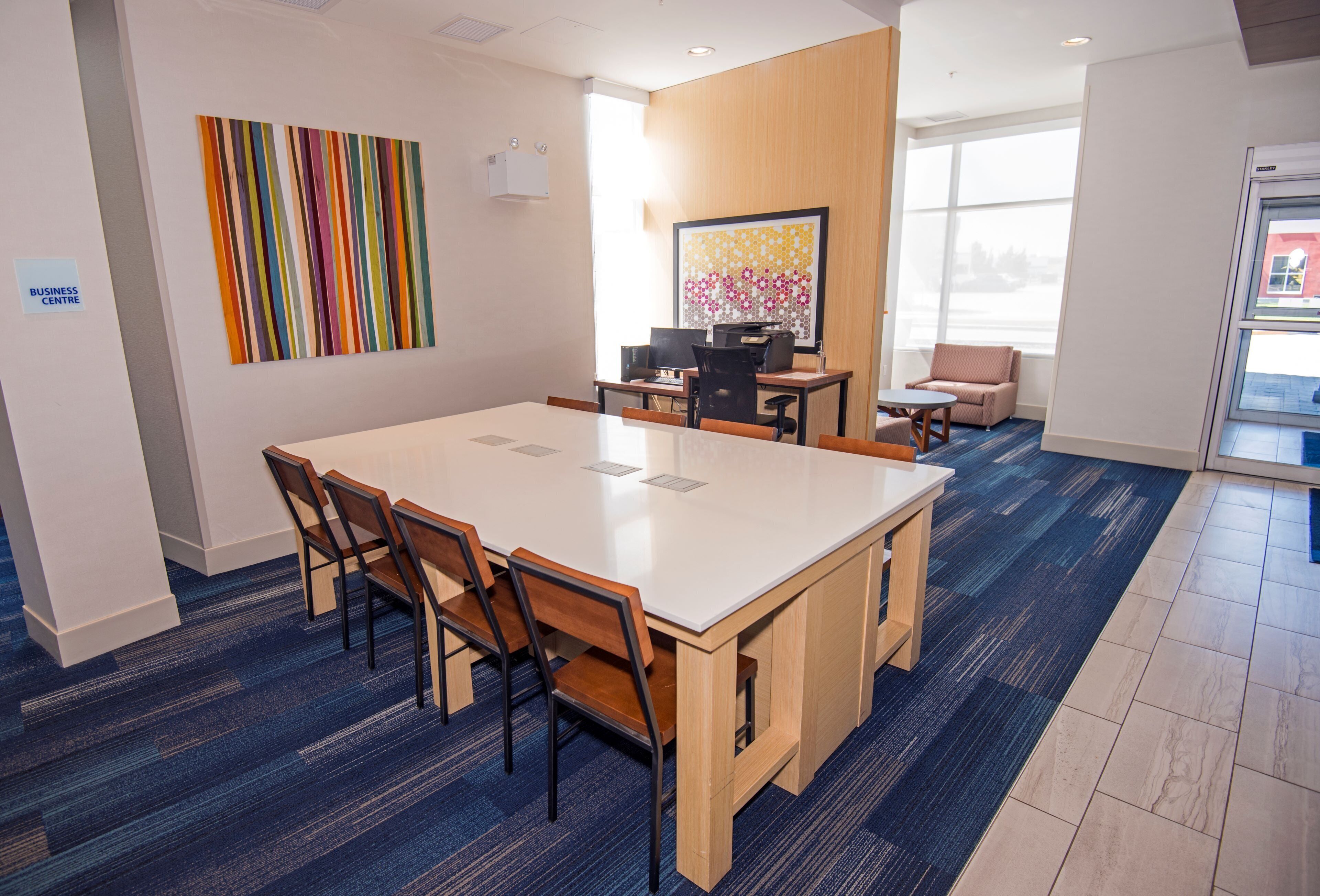 A conference room with a large table, chairs, a computer, and a window.