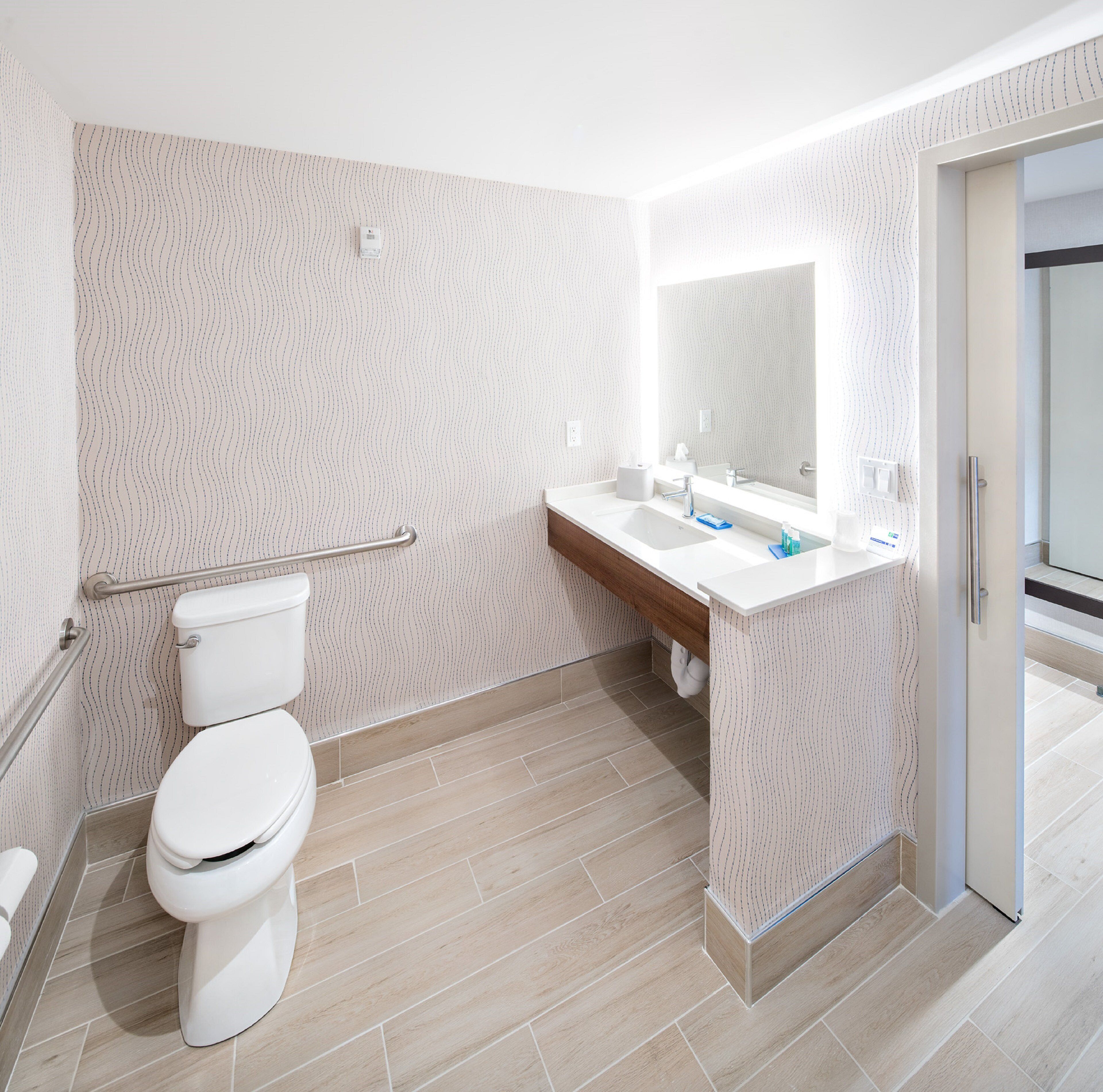 A modern bathroom with a toilet, sink, and mirror.